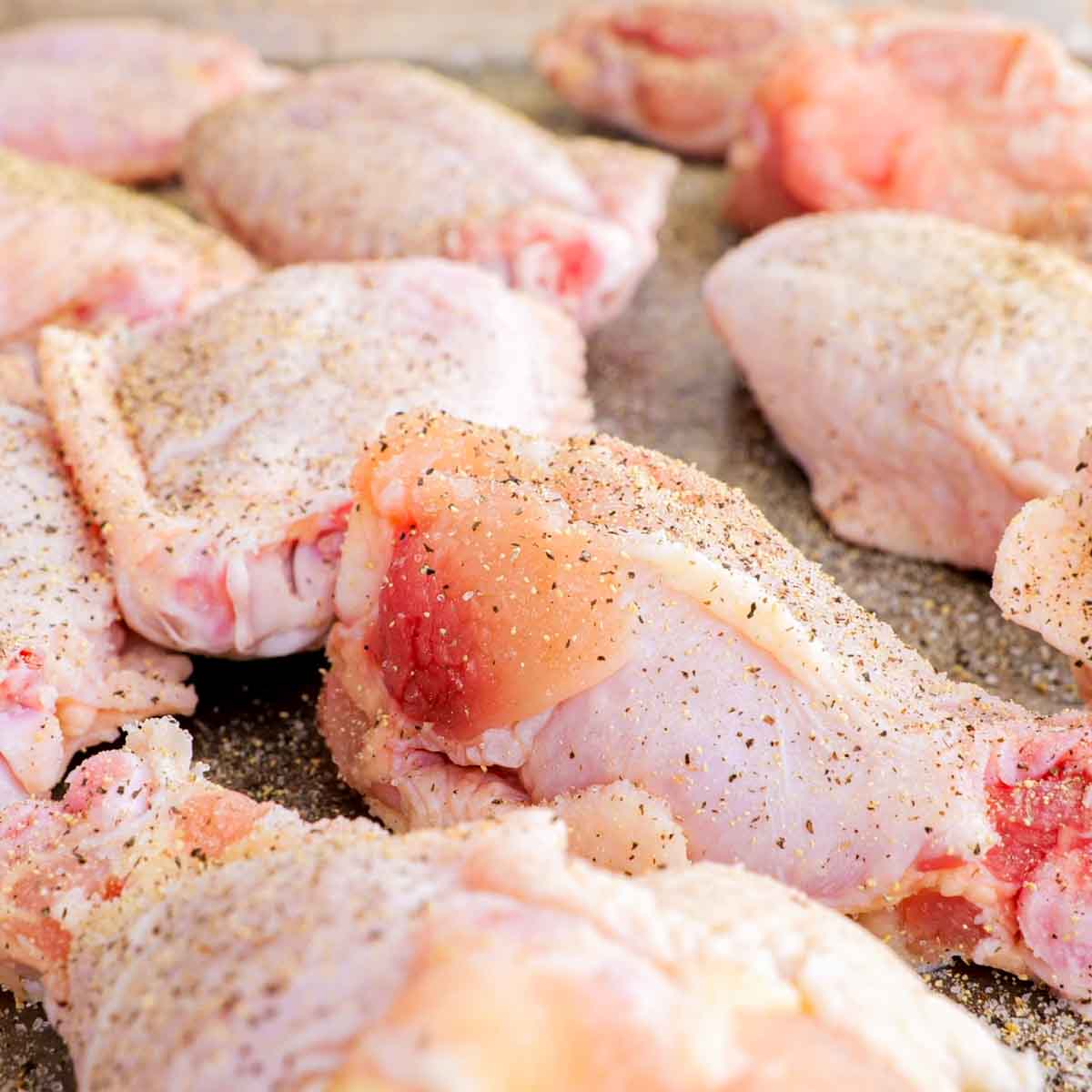 Chicken breasts on a baking sheet with seasonings to make Air Fryer Chicken Wings