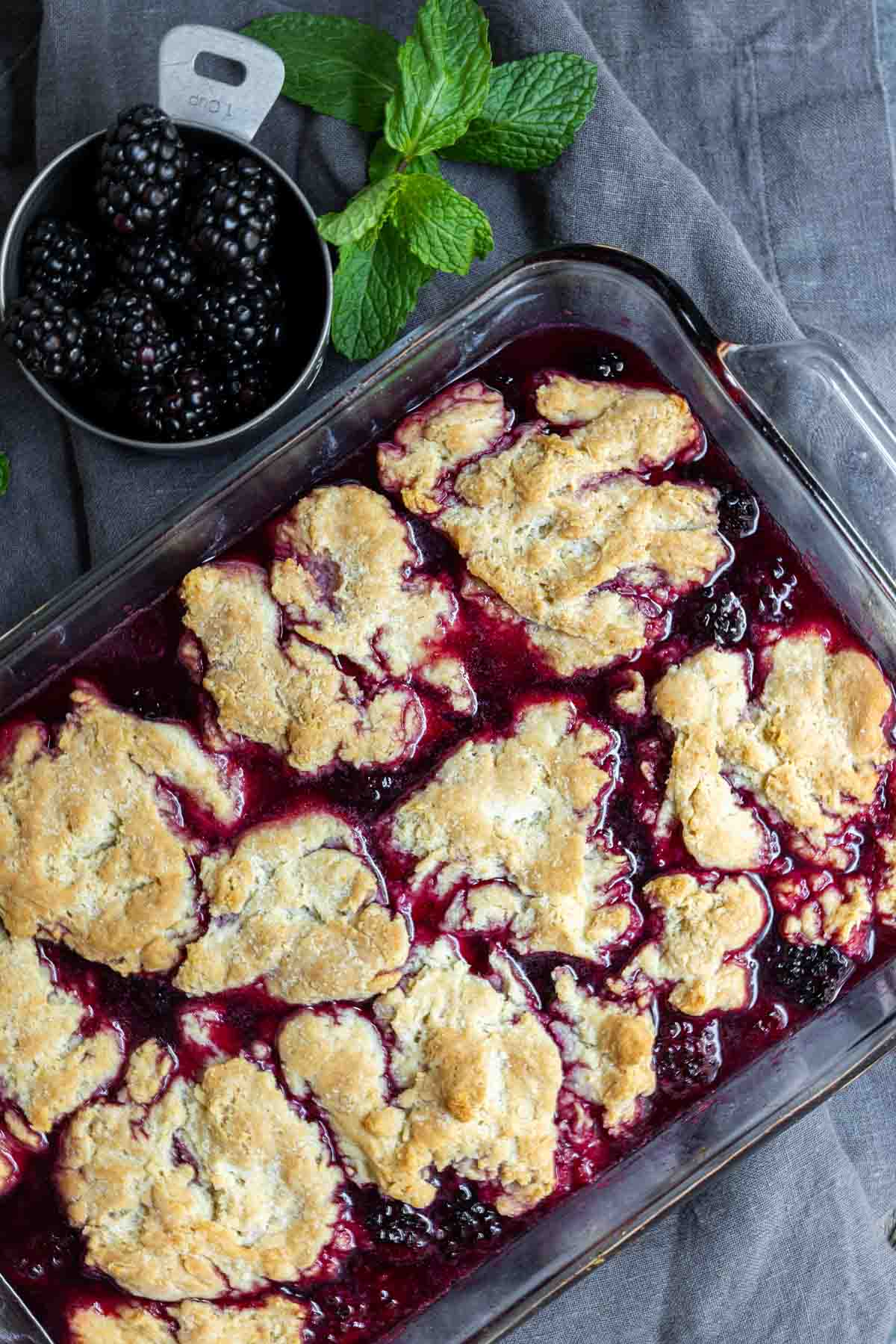 easy blackberry cobbler in dish with a cup of fresh blackberrys