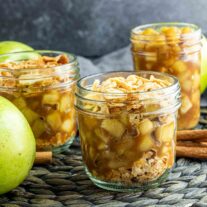 apple pie in a jar on a table with apples and cinnamon
