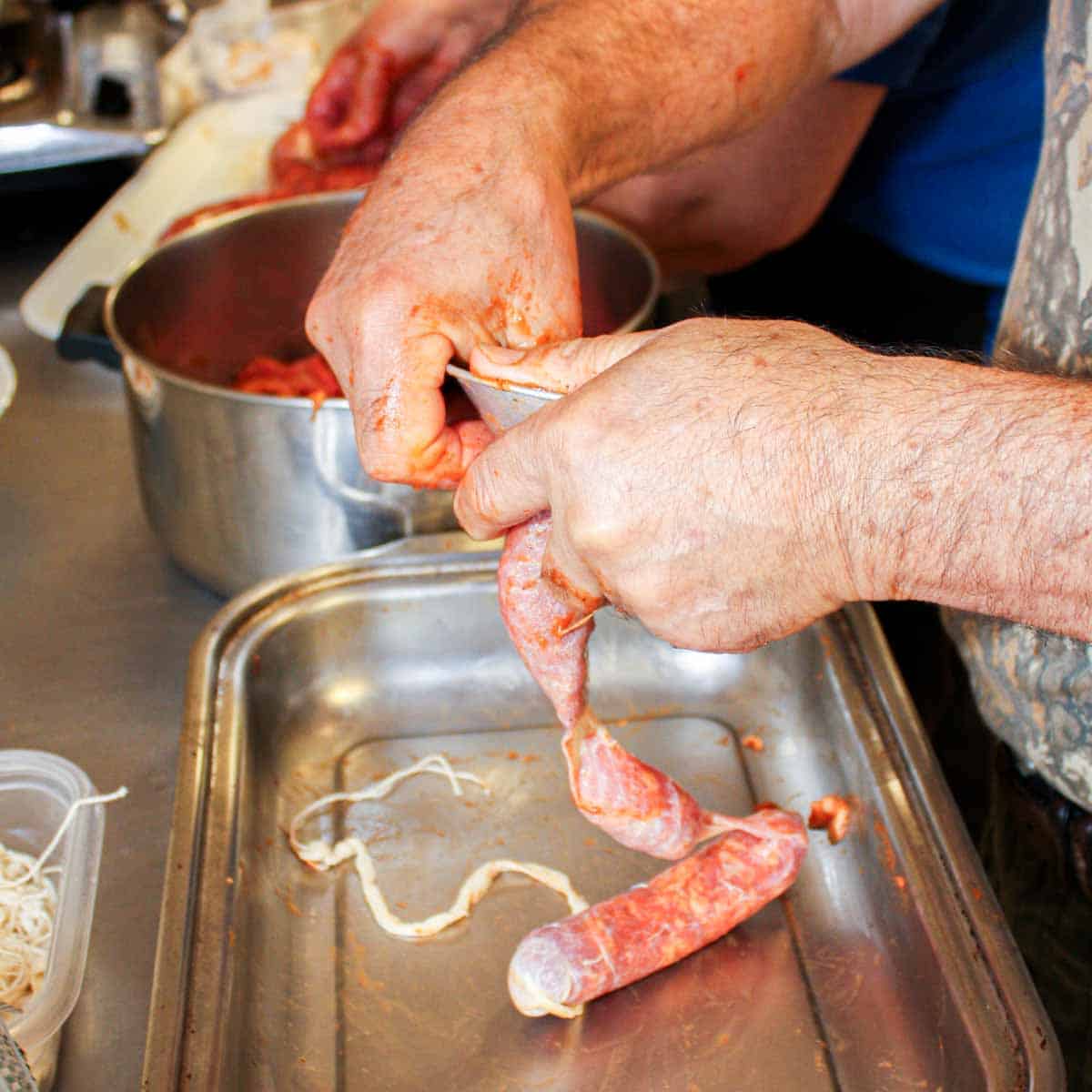 A man is preparing Portuguese sausage in a pan.