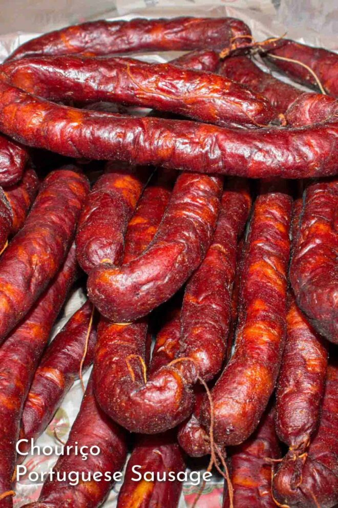 A pinterest imgae of A pile of Portuguese sausage on a table.