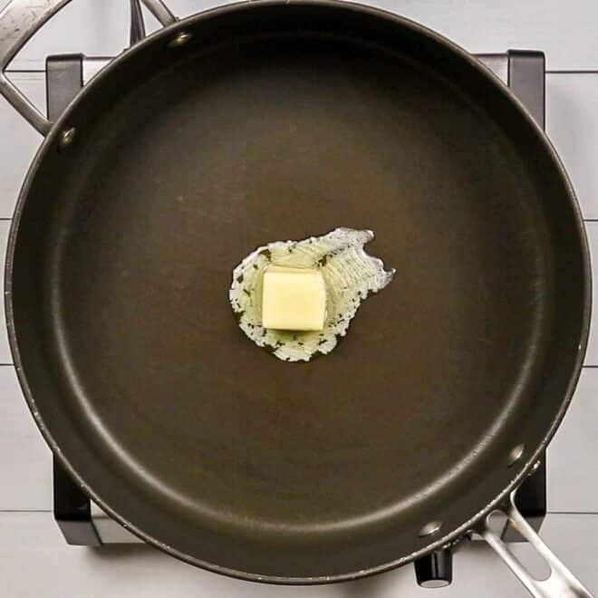 Butter in a frying pan on a stove top to make Creamed Corn