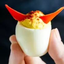 A person holding a Halloween Deviled Eggs with horns on it.