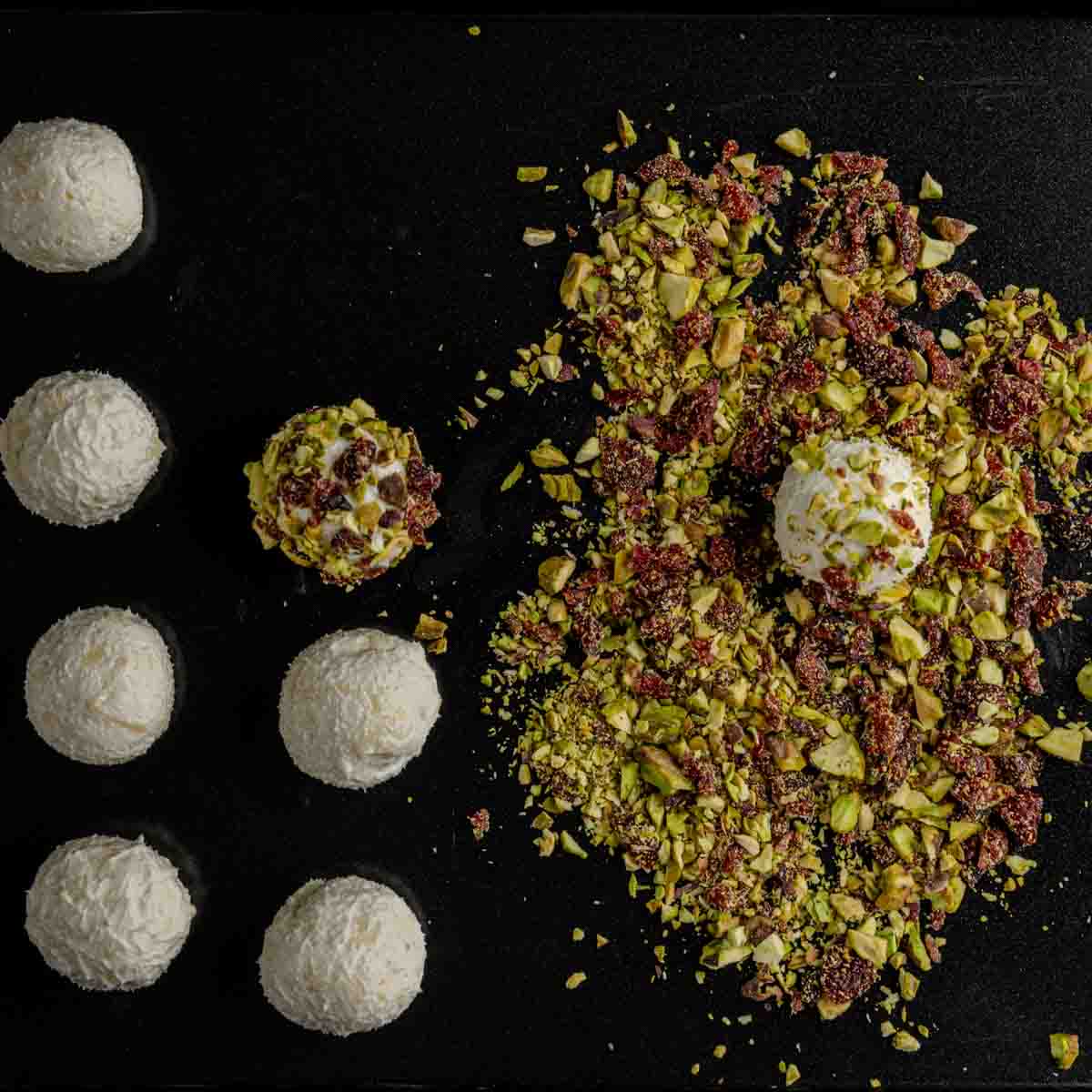 Pistachio and Ingredients for Mini Cheeseballs 3 Ways on a black plate.