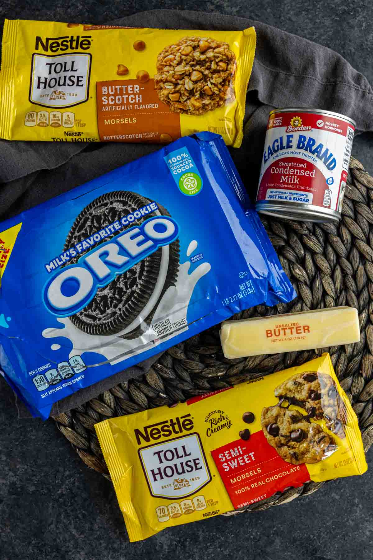 Oreos and ingredients to make Oreo Magic Bars on a wicker placemat.