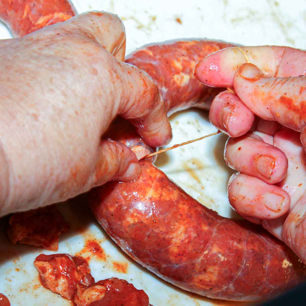 A person is putting a Portuguese sausage into a ring.