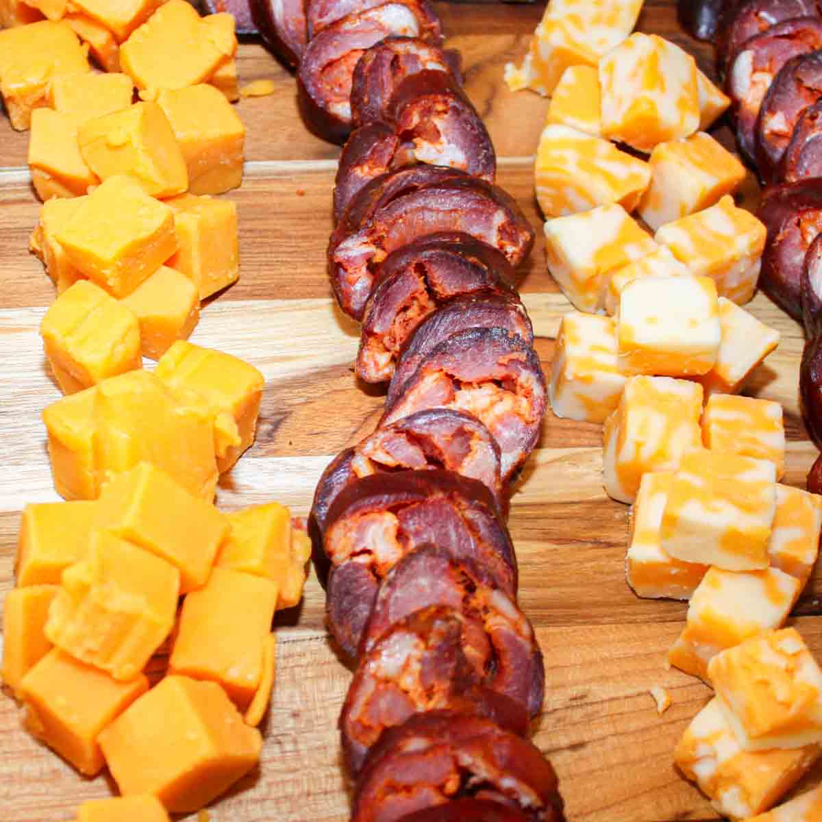 A tray of cheese and Portuguese sausage on a wooden board.