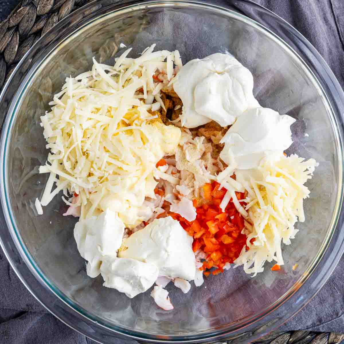A glass bowl filled with cheese, peppers, and other ingredients.