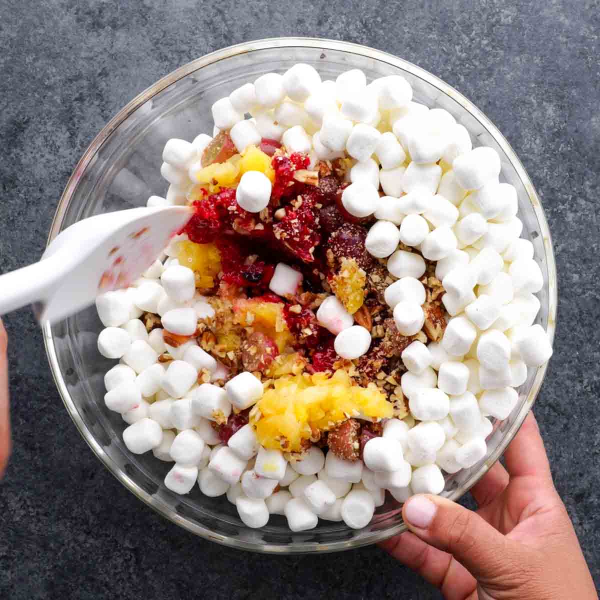 A person scooping marshmallows into a bowl to make Cranberry Fluff