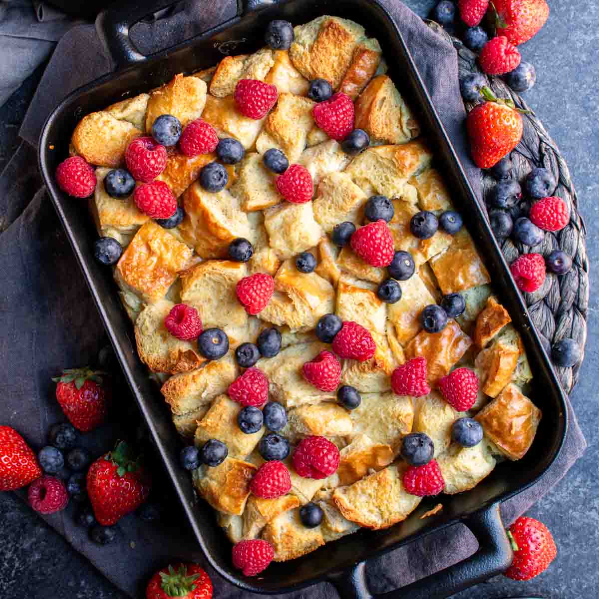 Overnight French Toast Bake with berries and blueberries in a cast iron pan.