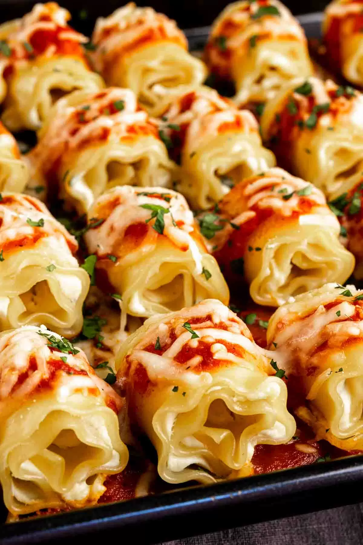 A tray of Mini lasagna appetizers with sauce and parmesan cheese.