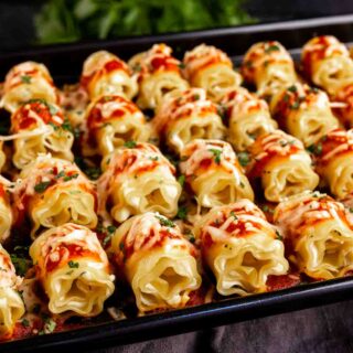 A tray of mini lasagna appetizer with sauce and parmesan cheese.