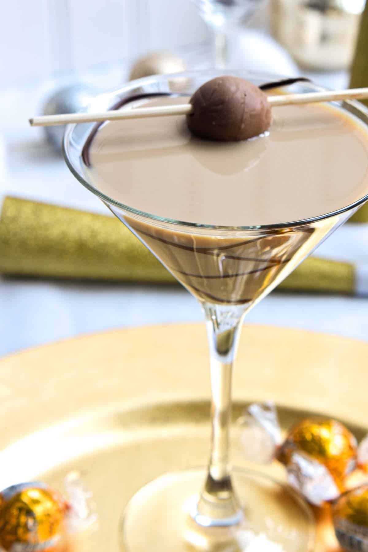 A chocolate martini with chocolate and a candy cane on a gold plate.