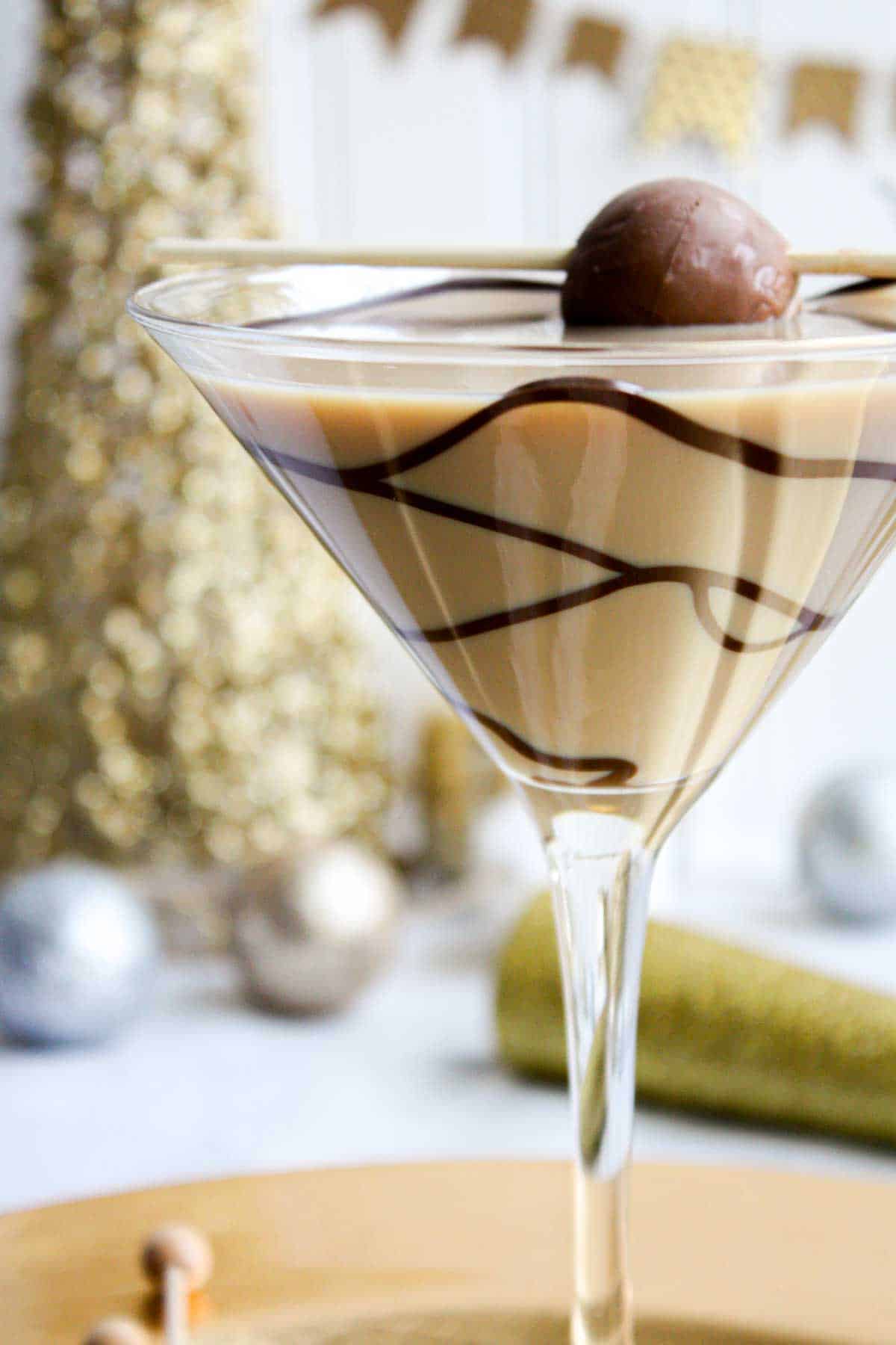 A chocolate martini in a gold glass with chocolate on top.