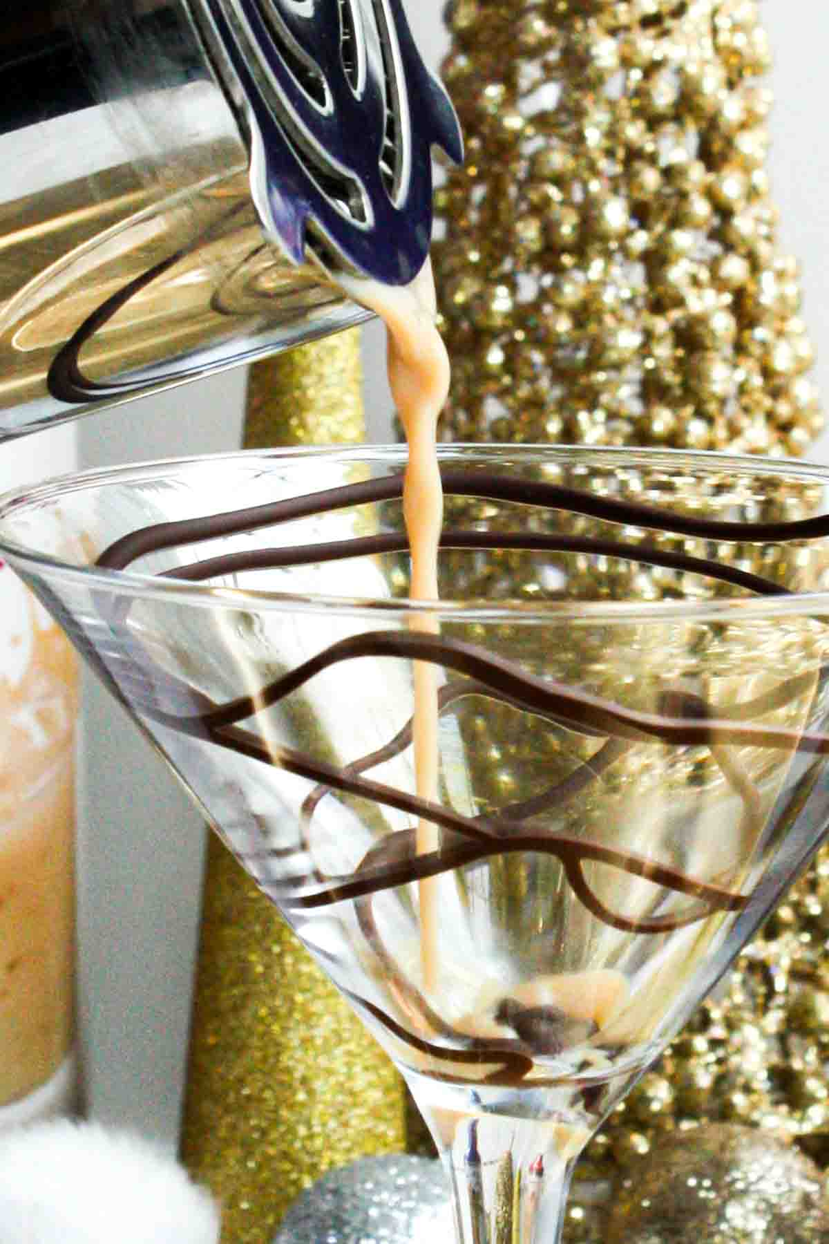 A martini glass with a chocolate martini being poured into it.