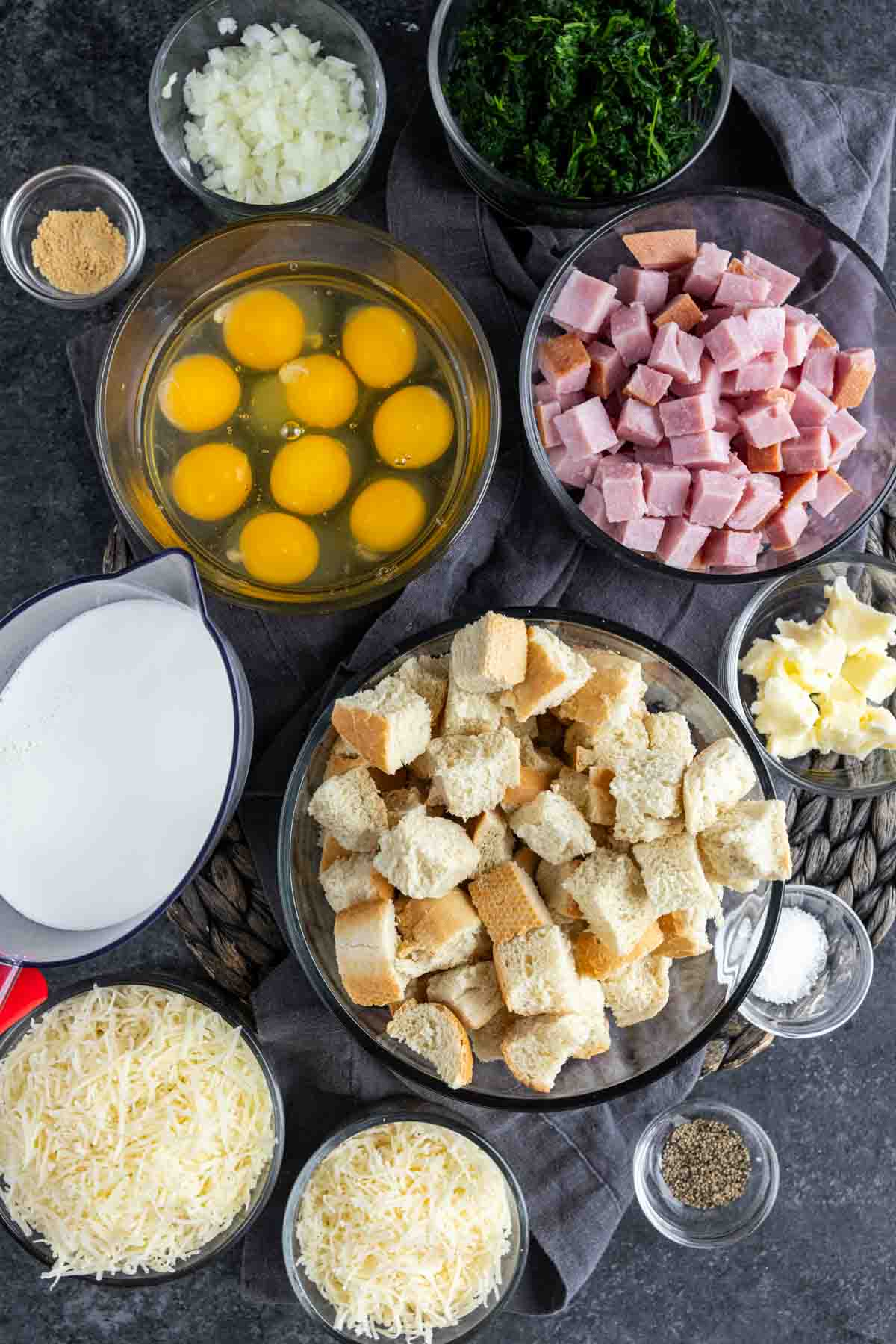 A bowl of eggs, bread, ham, cheese and other ingredients to make Ham and Cheese Strata