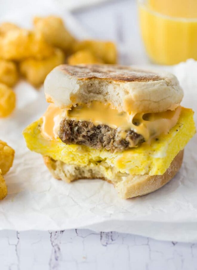 A breakfast sandwich with cheese and tater tots.