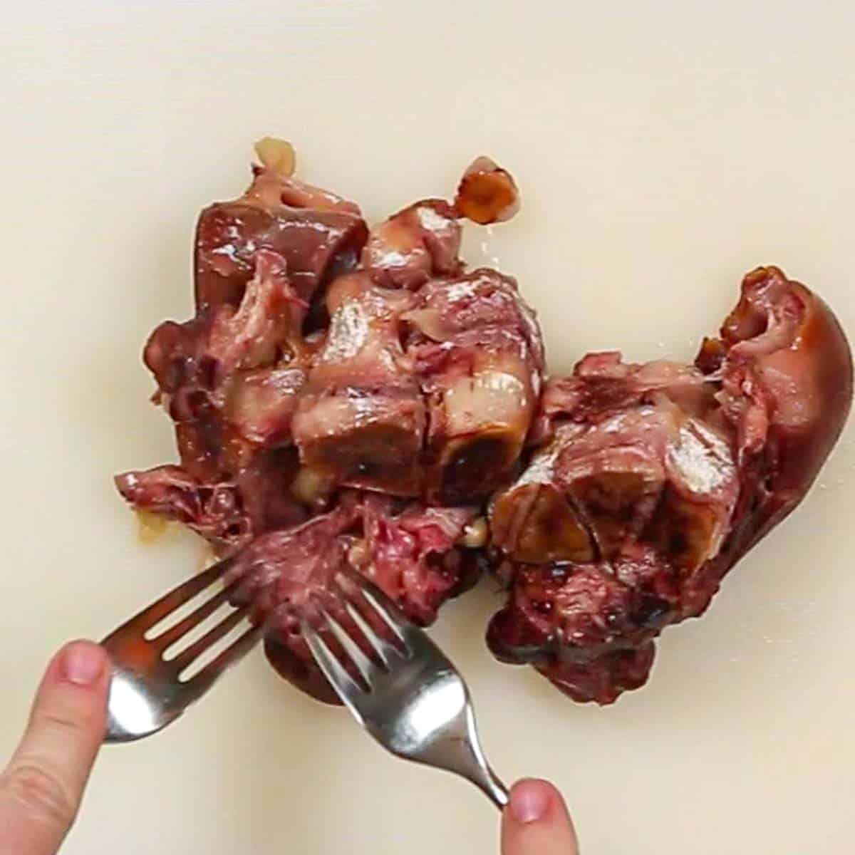 A person cutting up a piece of ham with a fork for Navy Bean Soup