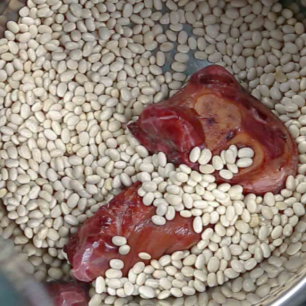 A bowl with ham and beans in it to make Navy bean soup