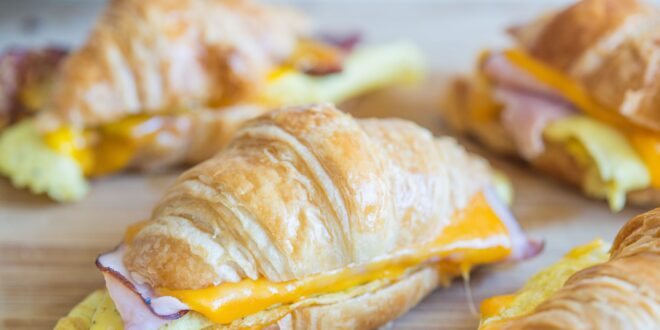 Ham and cheese croissants on a cutting board.