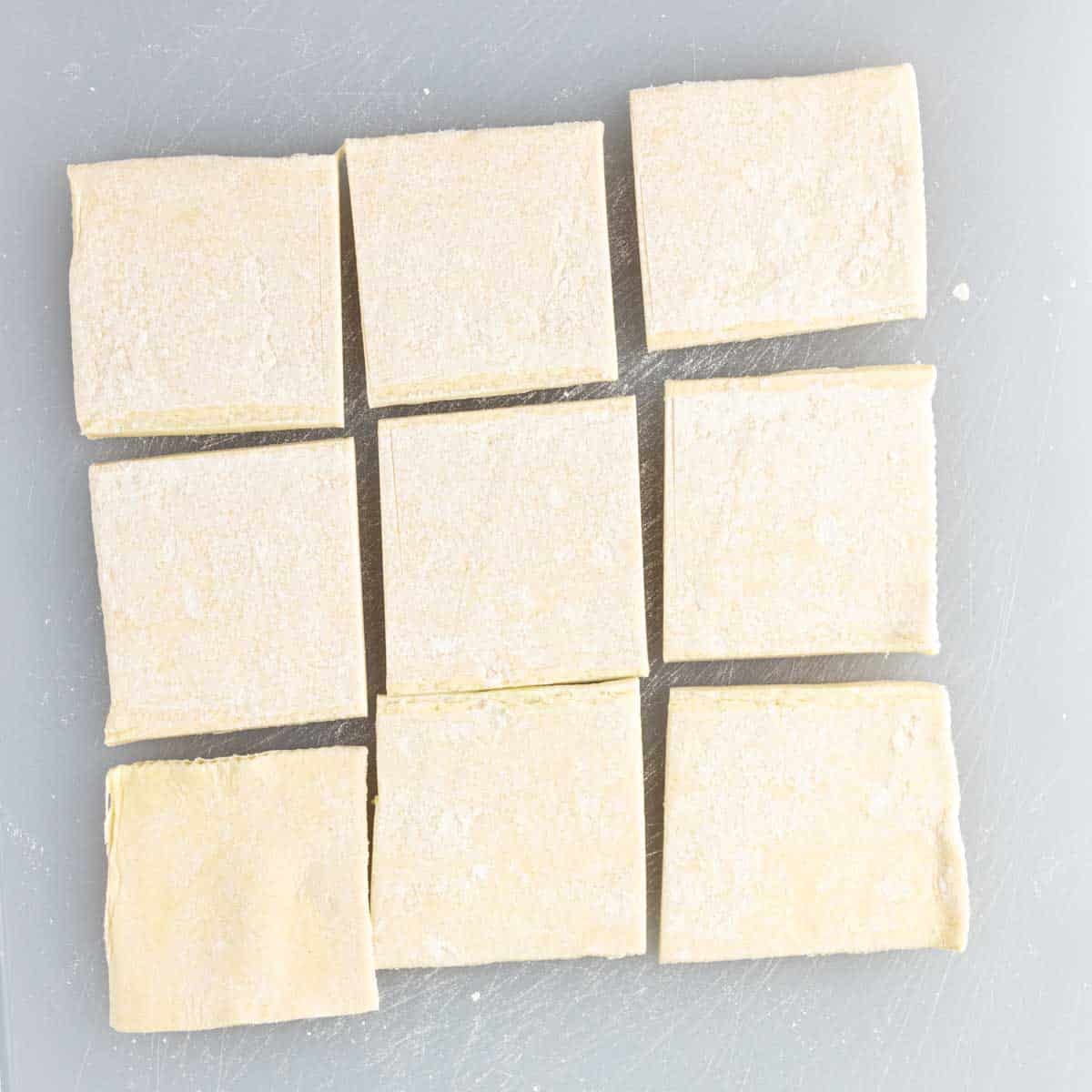 Squares of pastry dough are laid out on a cutting board to make Spinach Puffs