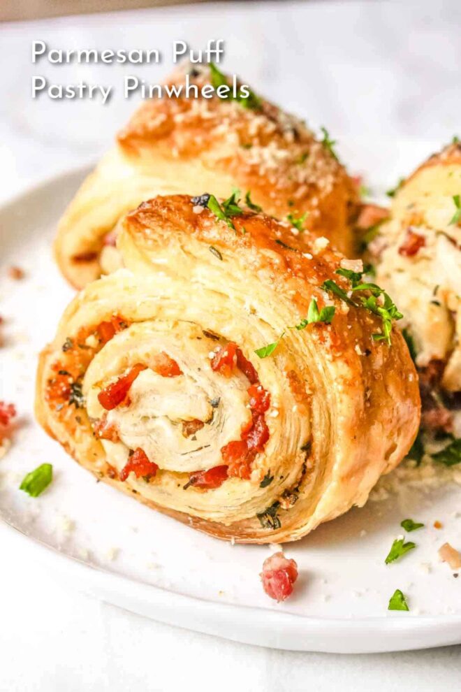 Parmesan puff pastry rolls on a white plate.