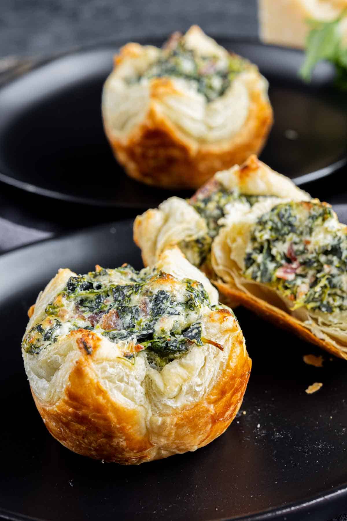 Spinach Puffs on a black plate.