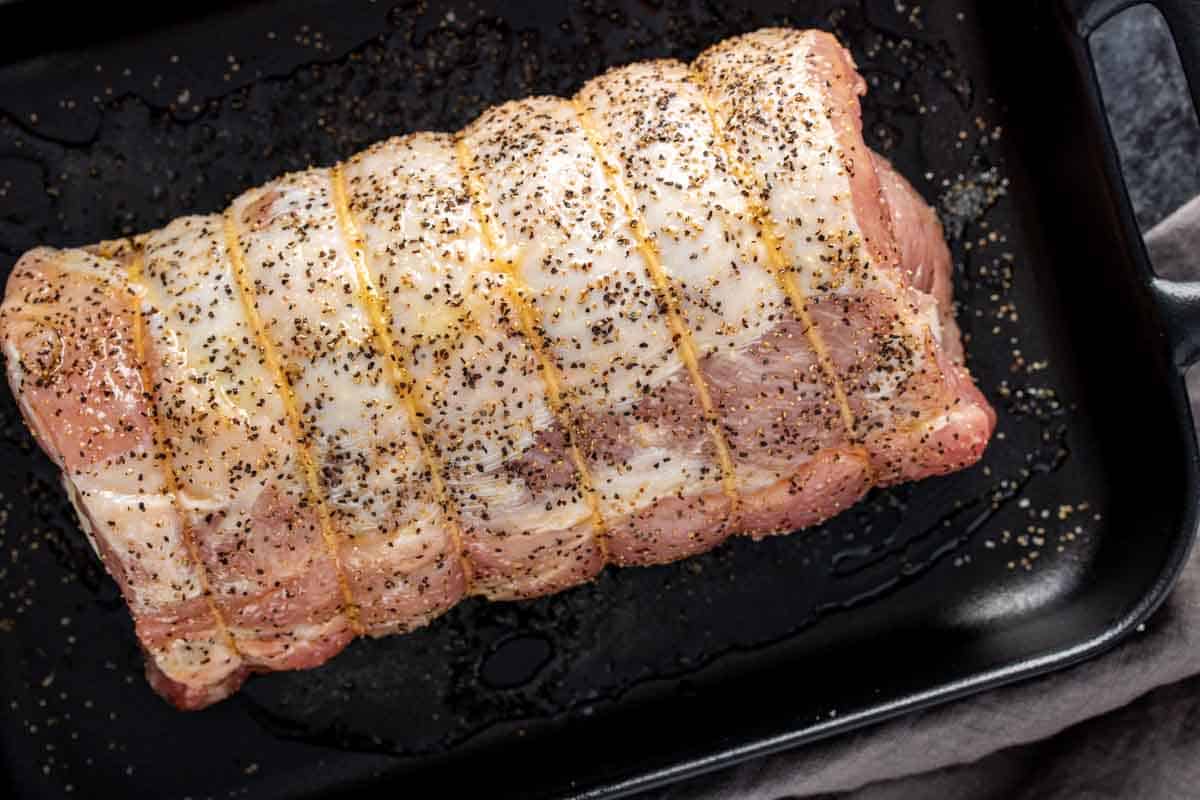 Provolone and Prosciutto Stuffed Pork Loin on a baking sheet with seasonings.