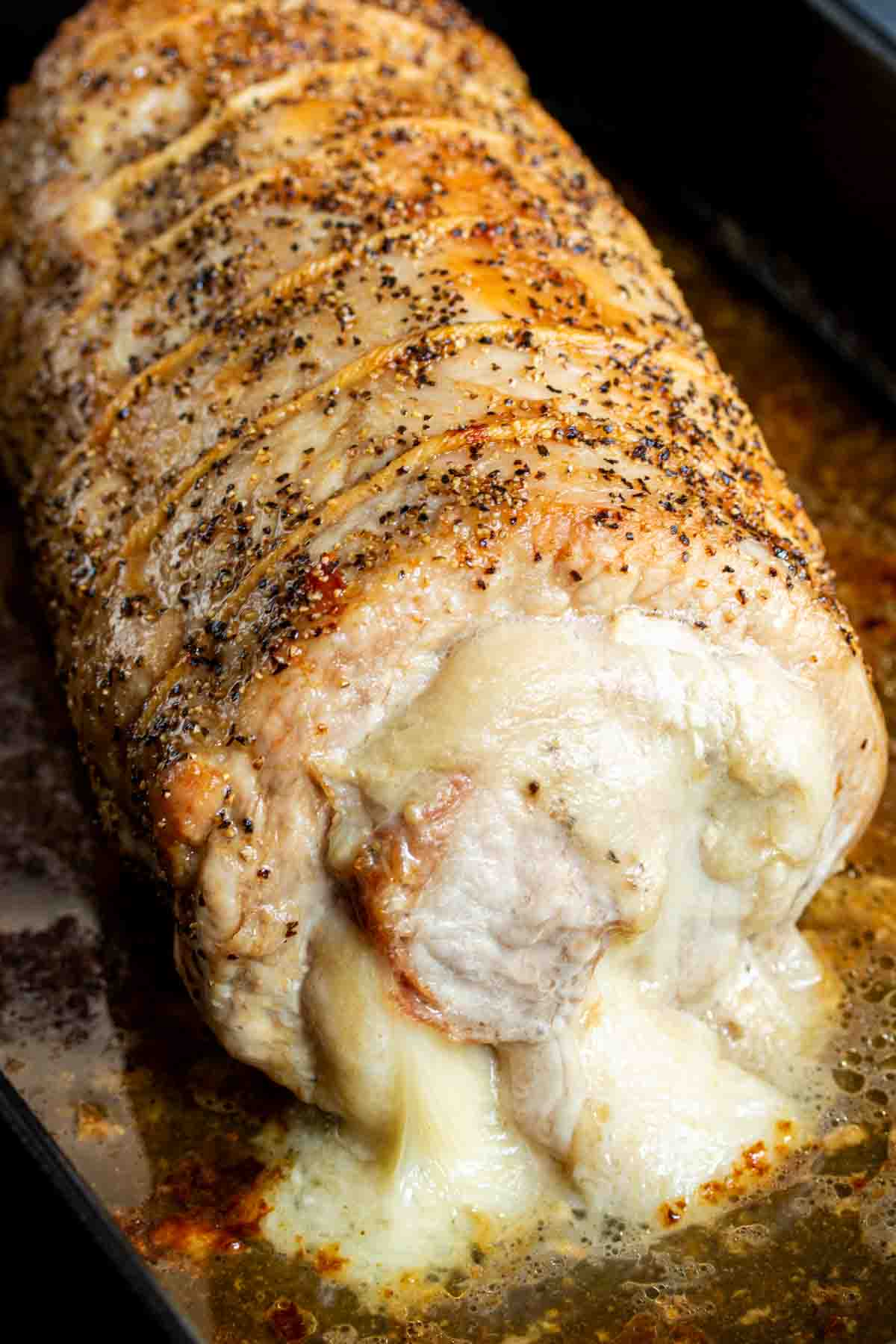Provolone and Prosciutto Stuffed Pork Loin and herbs in a baking pan.