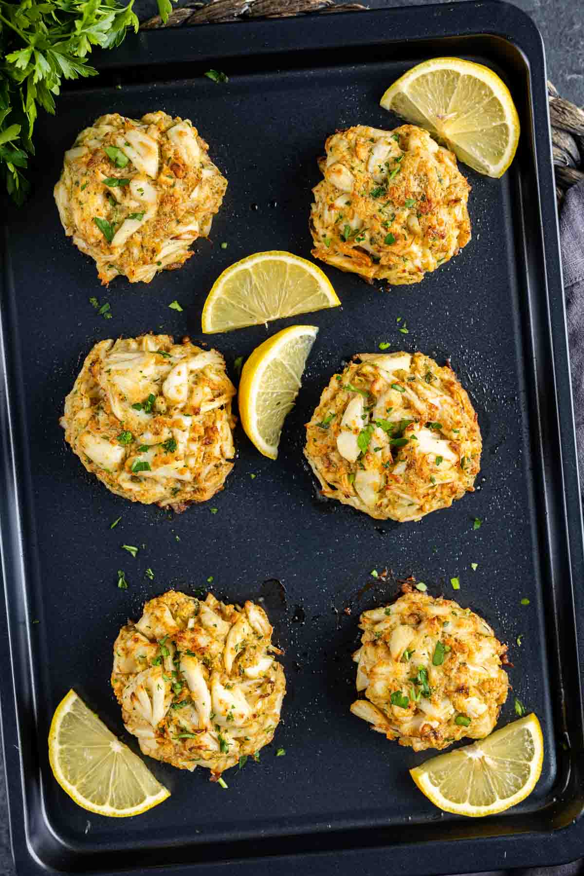 A tray of Maryland Crab Cakes with lemon slices.