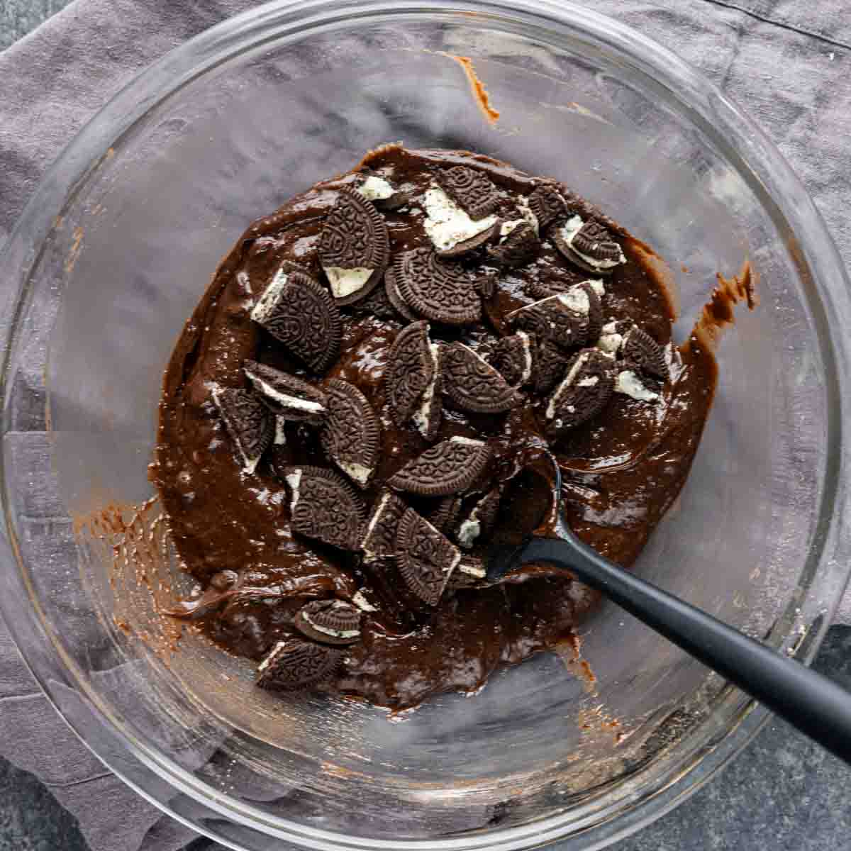 Oreo muffins batter in a bowl with a spoon.