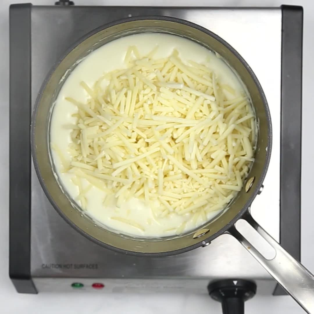 Melted cheese in a pan on a white surface to make asparagus casserole