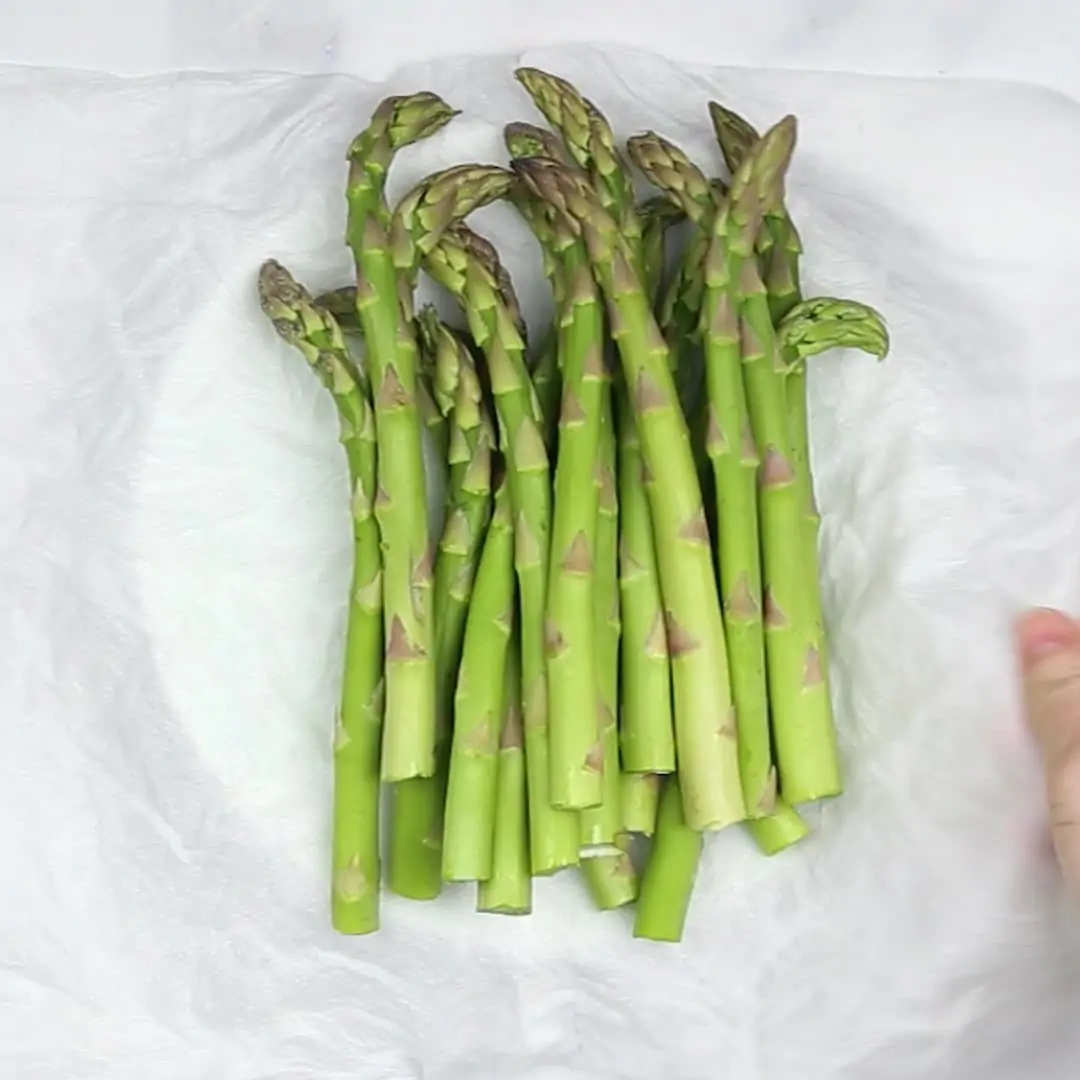 A bunch of steamed asparagus on a white paper to make Asparagus Casserole