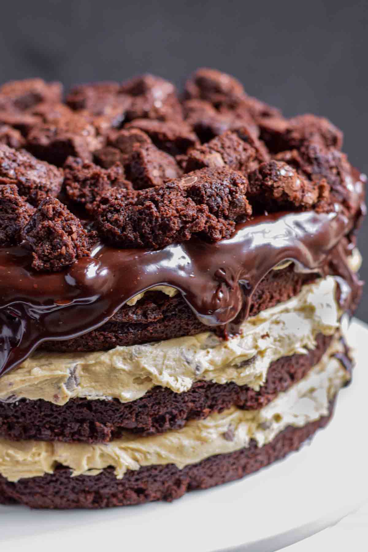 A stack of chocolate chip cookie brownie cake layered cake on a plate.
