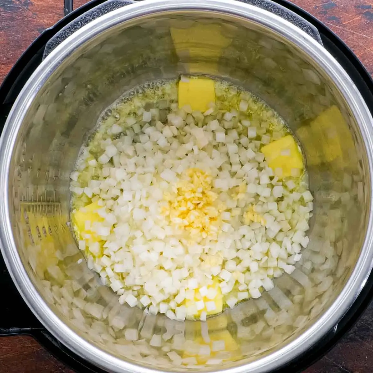 An instant pot filled with onions and garlic for Instant Pot Butter Chicken