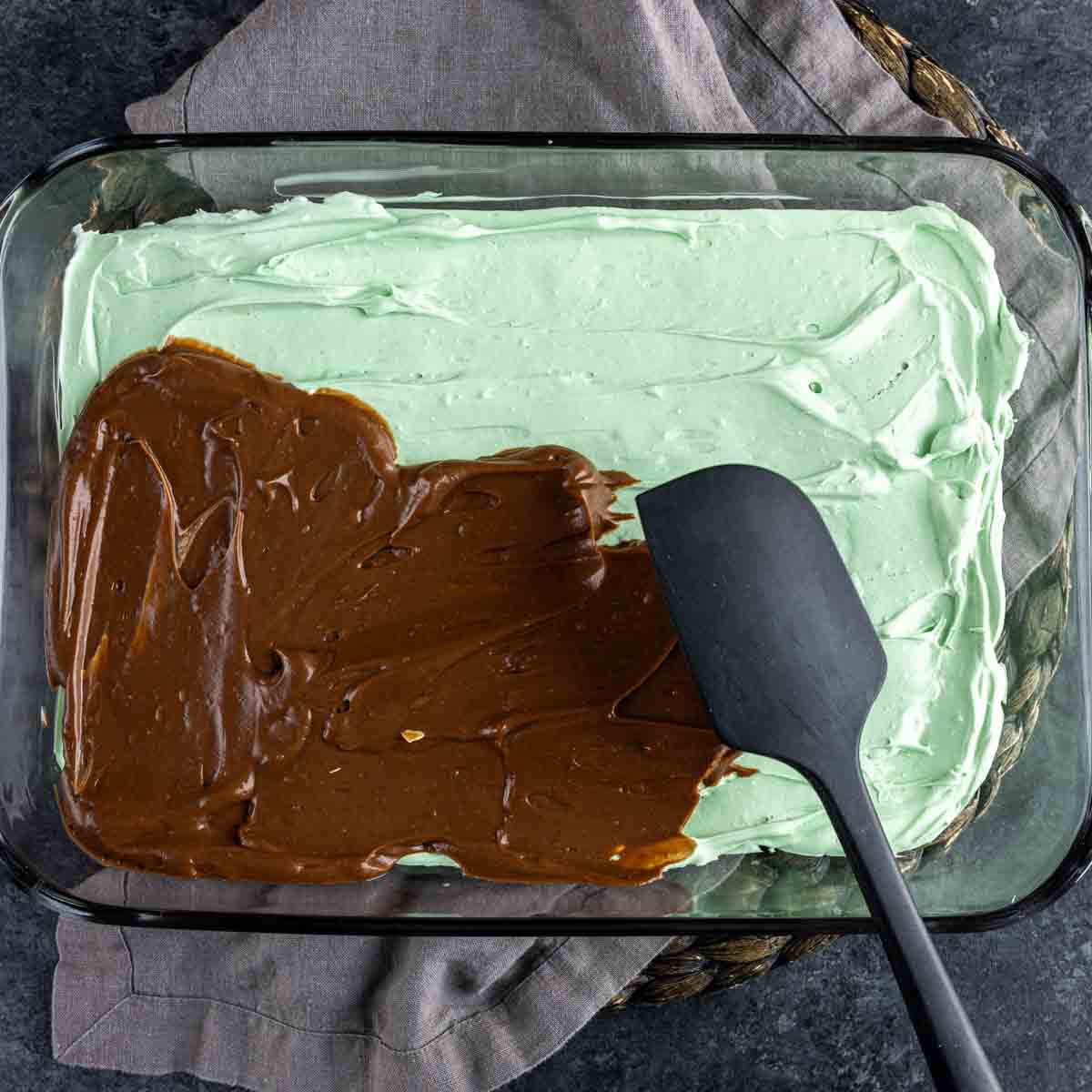 A glass baking dish with mint oreo dessert and a spatula.