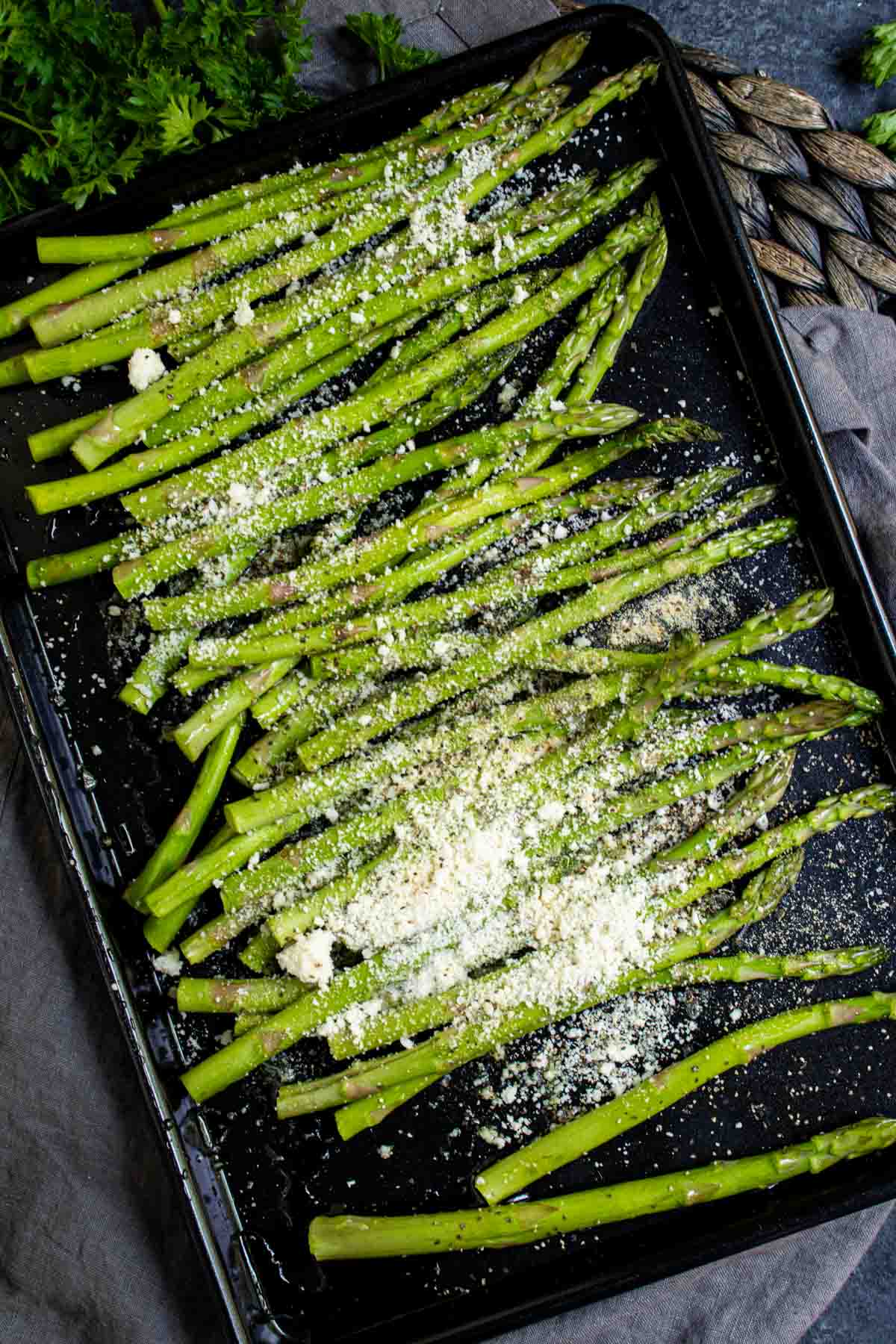Air Fryer Asparagus sprinkled with parmesan cheese on a baking sheet.