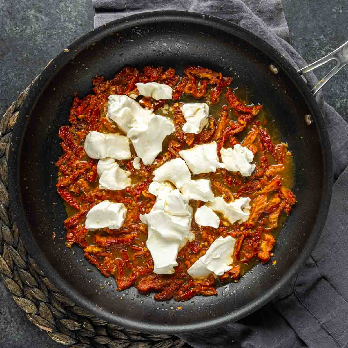 Tomato sauce with dollops of cheese in a frying pan for Chicken Florentine Casserole