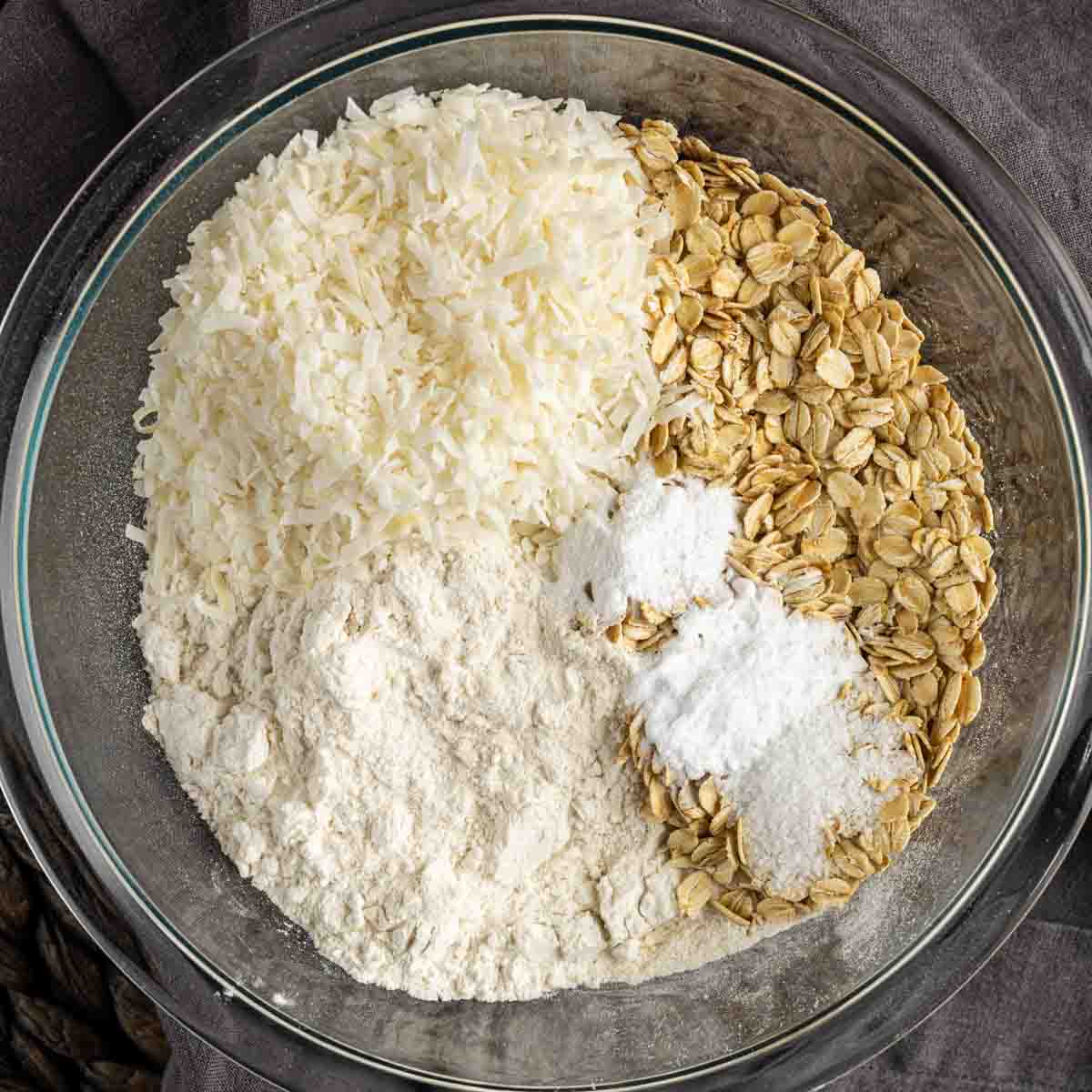 Oats, flour, sugar and butter in a glass bowl to make Crispy Coconut Cookies