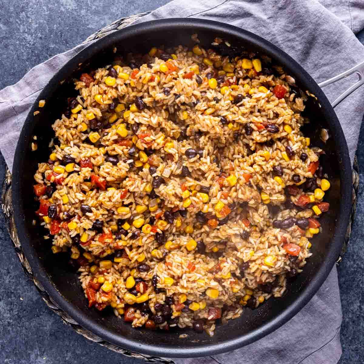 A skillet filled with One Pot Mexican Chicken and Rice, beans, corn, and vegetables.