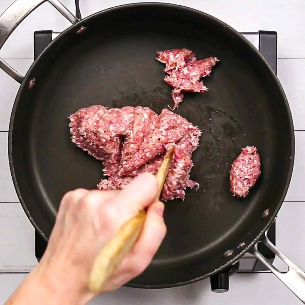 Breaking apart ground meat in a pan for Spinach and Sausage Quiche