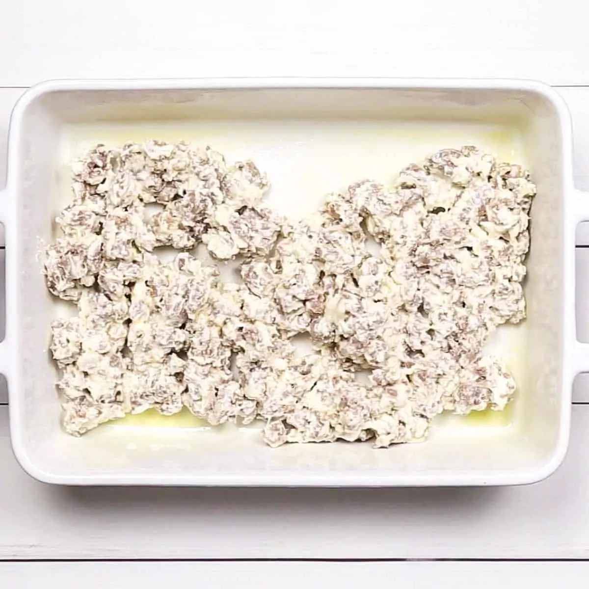 sausage cream cheese mix arranged in a baking dish to make Spinach and Sausage Quiche
