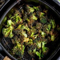 Air Fryer Broccoli with seasoning in an air fryer basket.