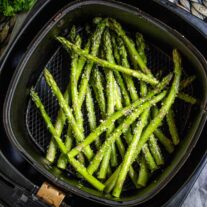 Air Fryer Asparagus with seasoning in an air fryer basket.