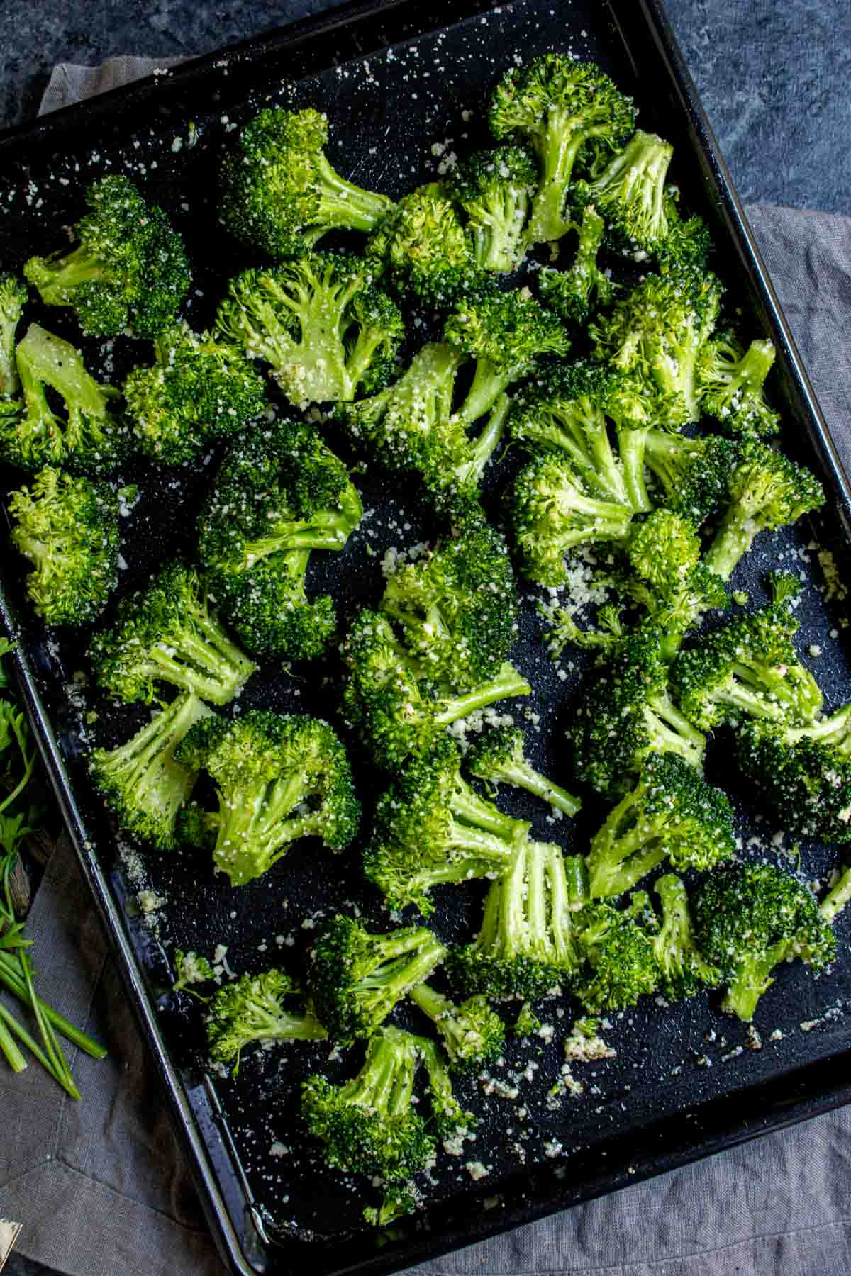 Air Fryer Broccoli florets seasoned with herbs on a baking tray, ready to be roasted.