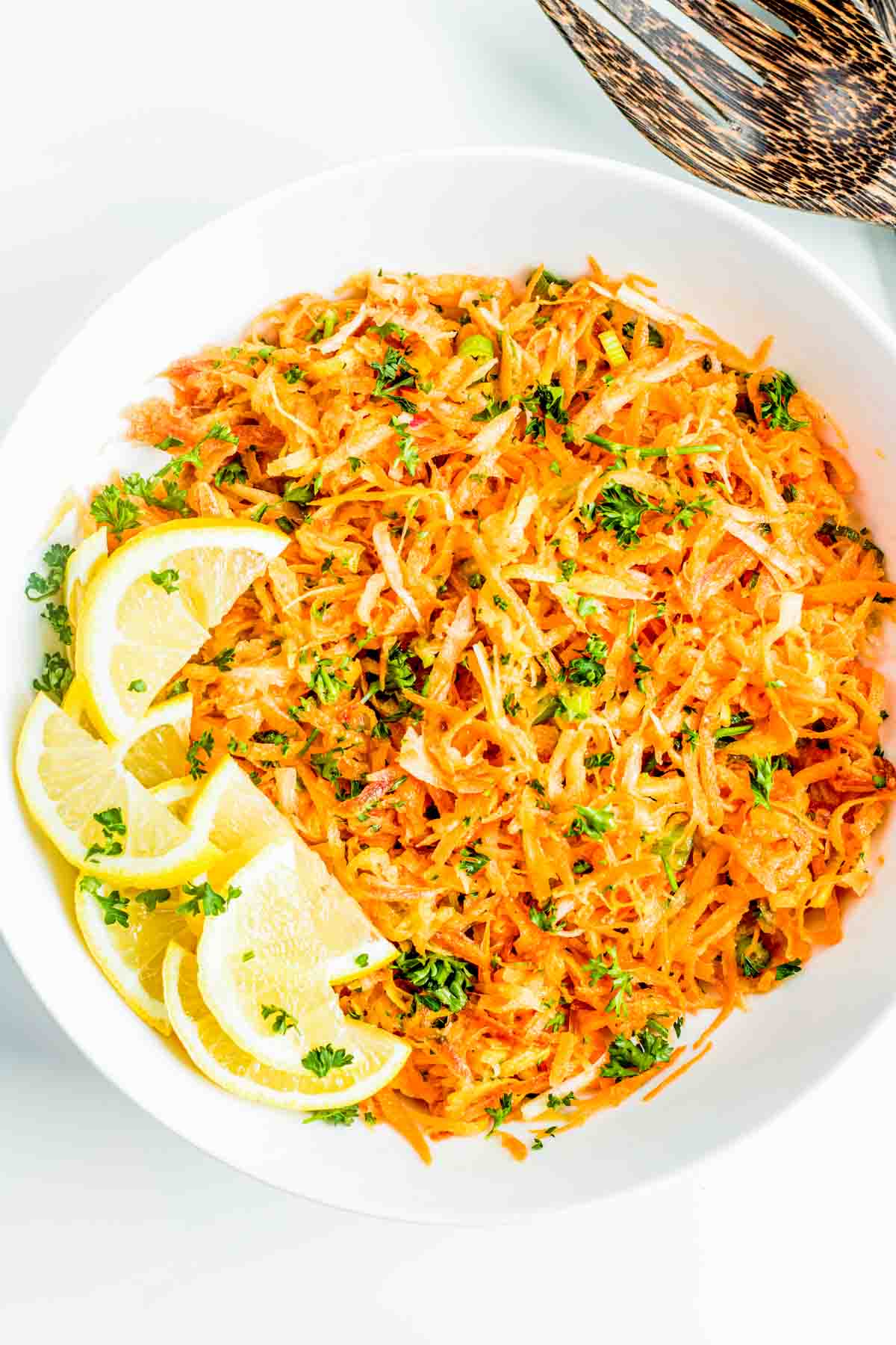 A plate of zesty lemon carrot salad garnished with chopped parsley.