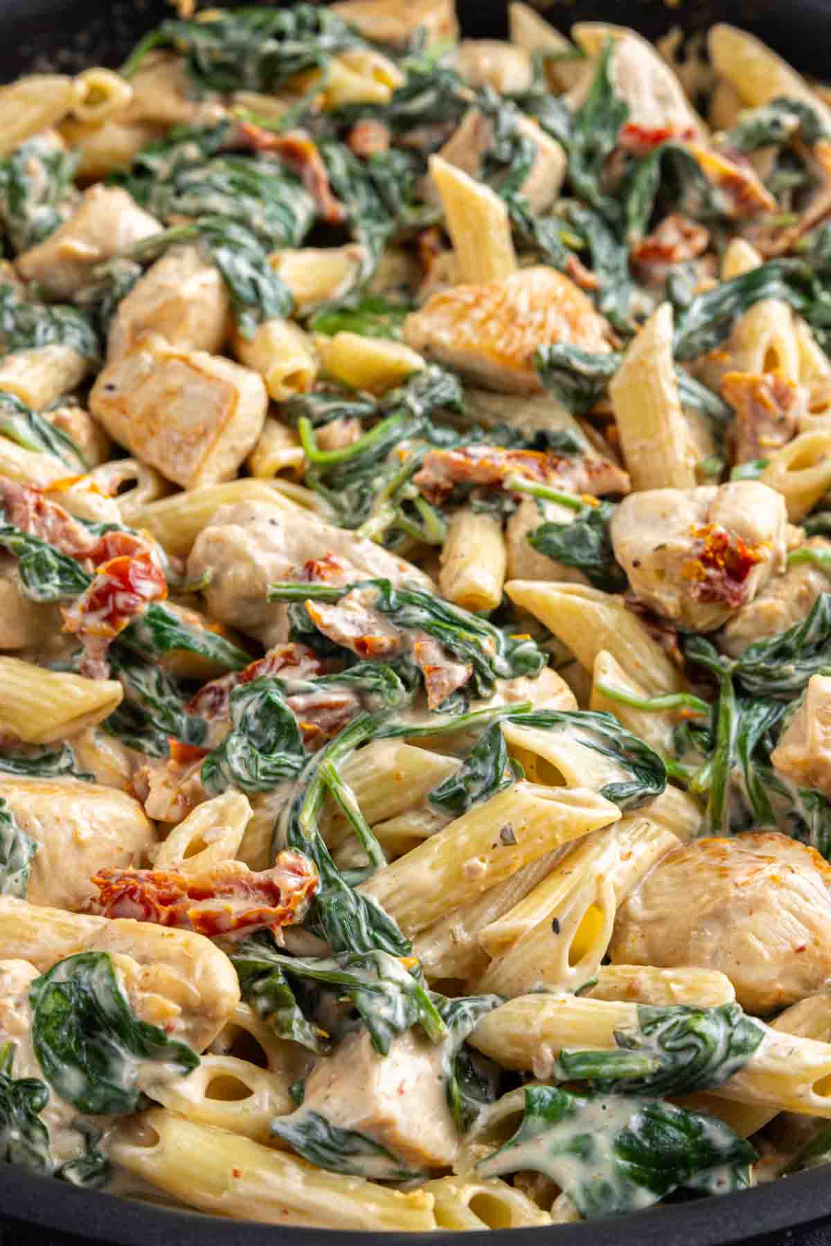 Creamy Chicken Florentine Casserole, spinach, and sun-dried tomatoes in a skillet.