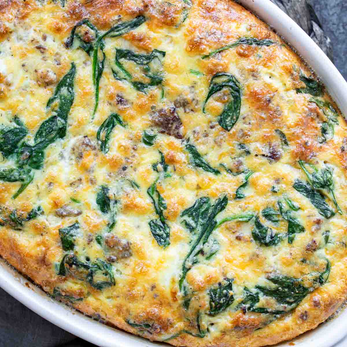 Freshly baked Spinach and Sausage Quiche in a white dish.