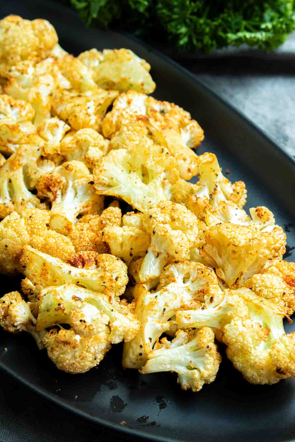 Roasted Cauliflower in the Air Fryer served on a black plate.