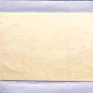 A sheet of raw pastry dough on parchment paper for an Asparagus Goat Cheese Tart